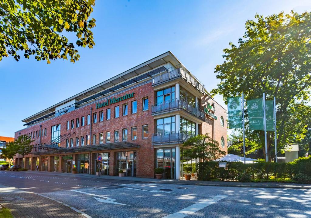 a large red brick building on a street at Hotel Mercator Itzehoe-Klosterforst in Itzehoe