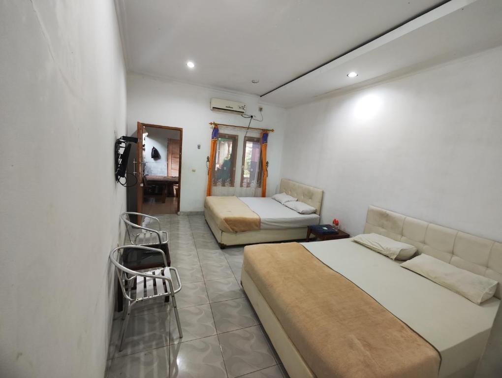 ein Schlafzimmer mit 2 Betten, einem Sofa und einem Stuhl in der Unterkunft Pondok Dewi in Pangandaran