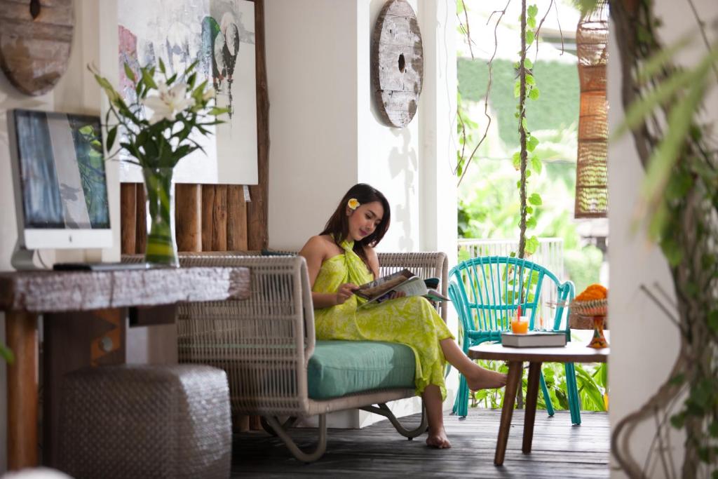 a woman sitting on a chair reading a book at Grandmas Plus Hotel Seminyak in Seminyak
