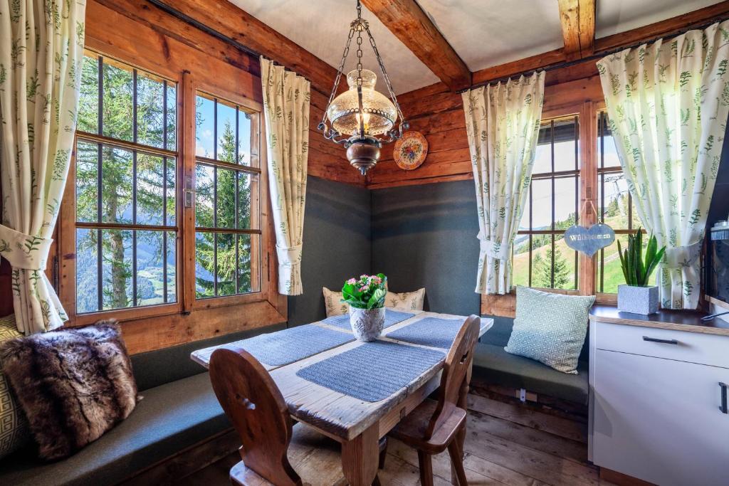 a dining room with a table and chairs and windows at Bergchalet Schennaberg in Schenna