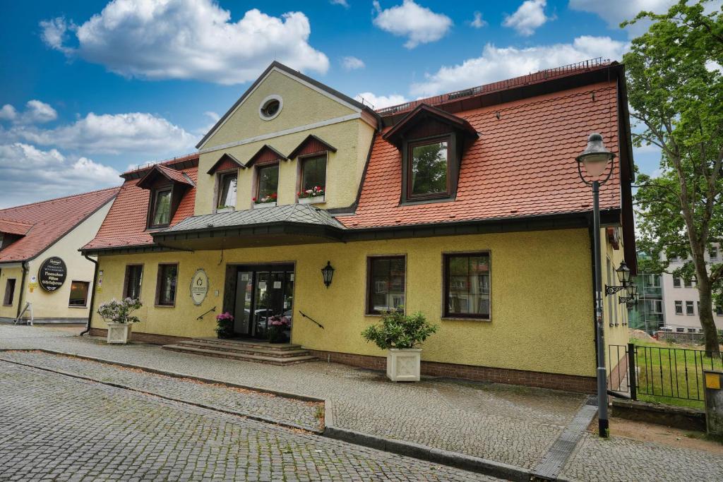 a yellow house with a red roof on a street at Hotel Sophienhof in Königs Wusterhausen