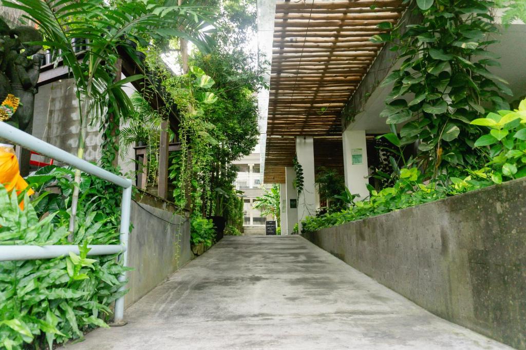 a walkway in a building with plants on it at Grandmas Plus Hotel Seminyak in Seminyak