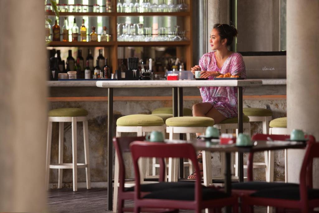 a woman sitting at a counter in a bar at Grandmas Plus Hotel Seminyak in Seminyak