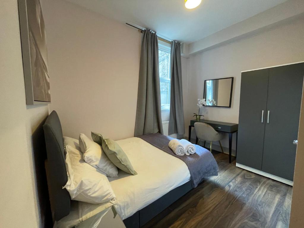 een slaapkamer met een bed, een bureau en een raam bij 43 Kimberly road apartment in Londen