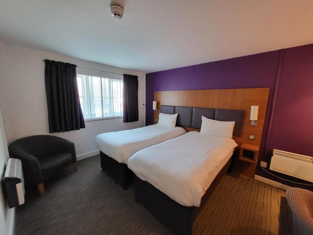 a hotel room with two beds and a chair at Tyger Inn Derby in Derby