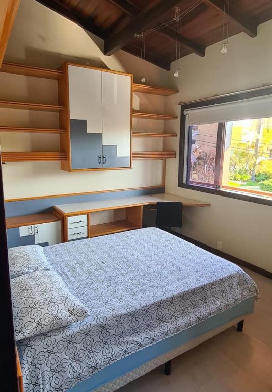 a bedroom with a bed and a desk and a window at Theora Quarto Amora in Blumenau