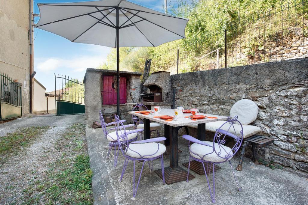 a table with chairs and an umbrella on a patio at Orizzonte Calmo in Borghetto Di Borbera