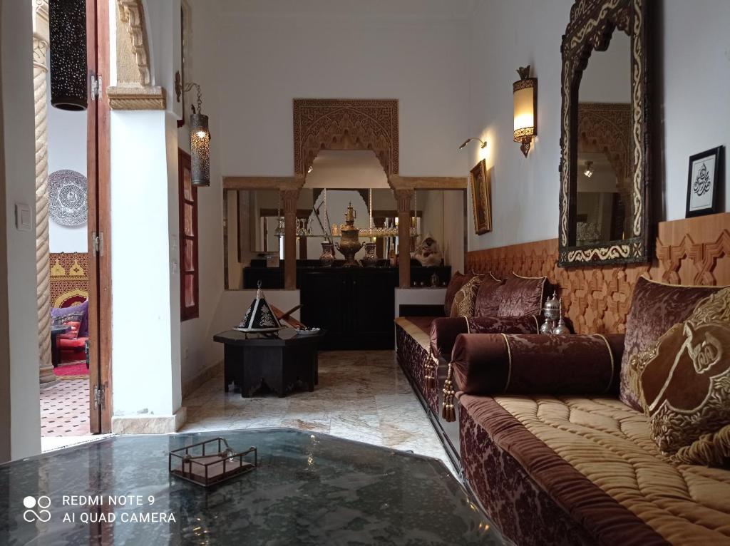 uma sala de estar com um sofá e uma mesa de vidro em Riad Dar Badiaa em Salé