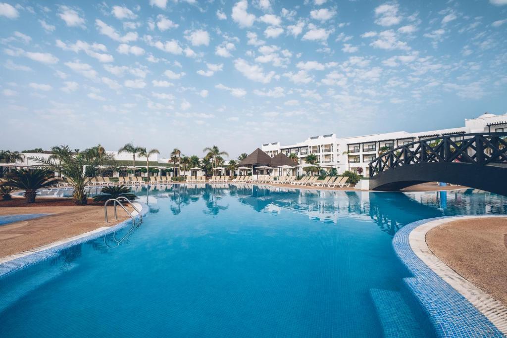 a large swimming pool in a resort with a bridge at Iberostar Saidia in Saidia 