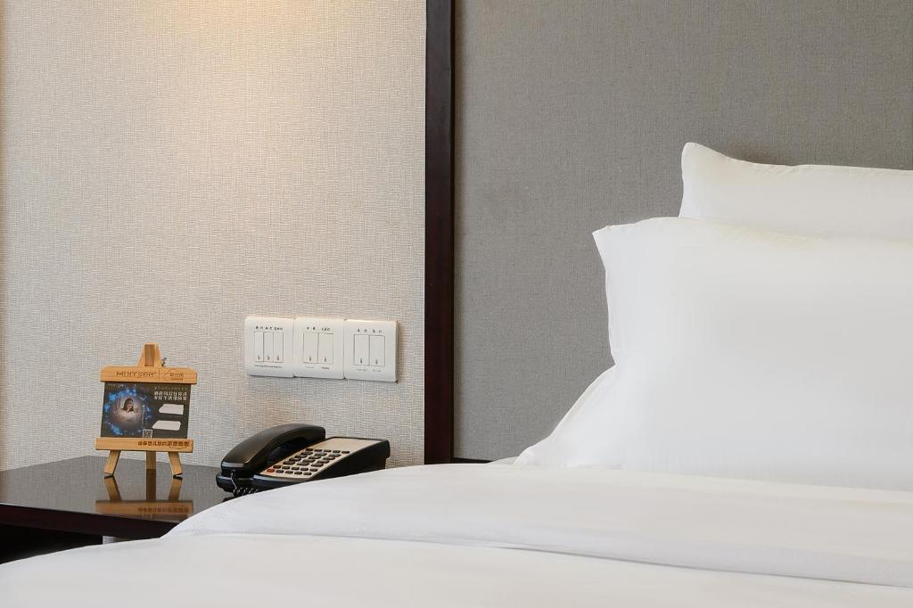 Schlafzimmer mit einem Bett und einem Telefon auf einem Tisch in der Unterkunft Foshan Rezen Select Pasonda Hotel in Foshan