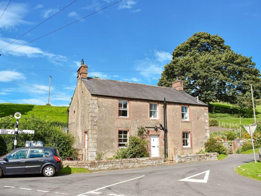 an old stone house with a car parked in front at Staffield Cottage in Kirkoswald