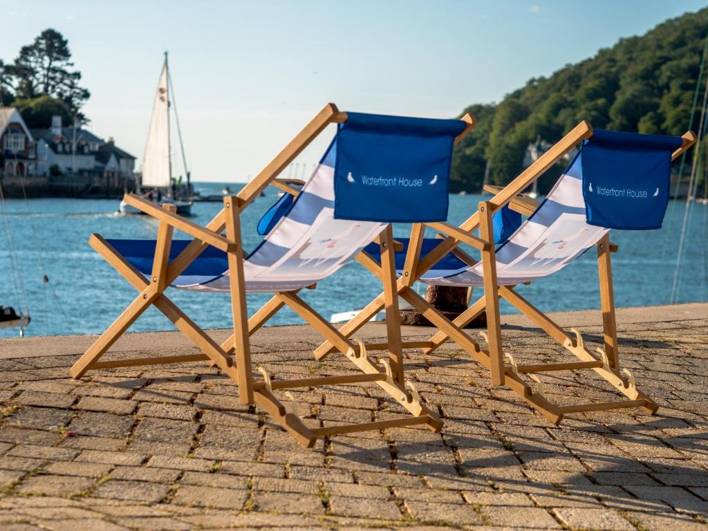 two chairs sitting on the beach near the water at Waterfront House in Dartmouth