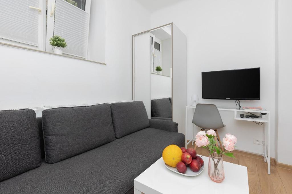 a living room with a couch and fruit on a table at Micro Apartment near Fort Mokotów in Warsaw