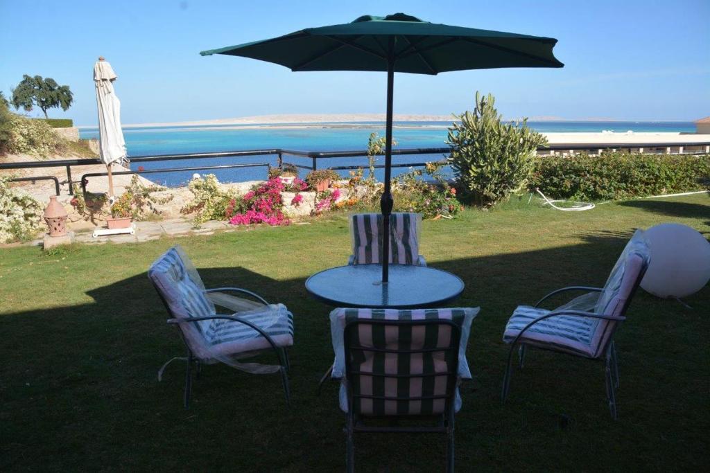 Prime Home The View Hurghada في الغردقة: طاولة وكراسي مع مظلة والمحيط