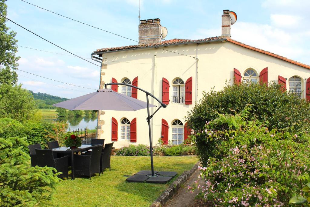 a house with a table and an umbrella in front of it at La Maison du Passeur in Availles-Limouzine