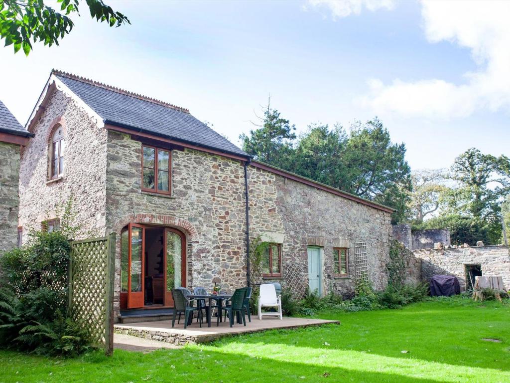 a stone house with a table and chairs in a yard at The Coach House - Uk35953 in South Pool