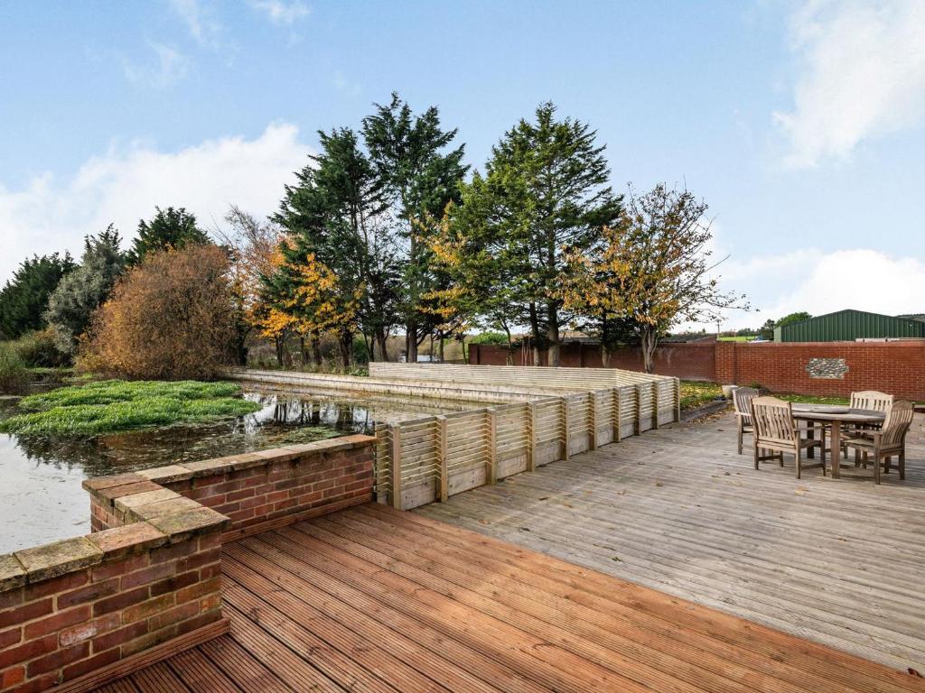 a wooden deck with a table and chairs next to a river at River View in Trimingham