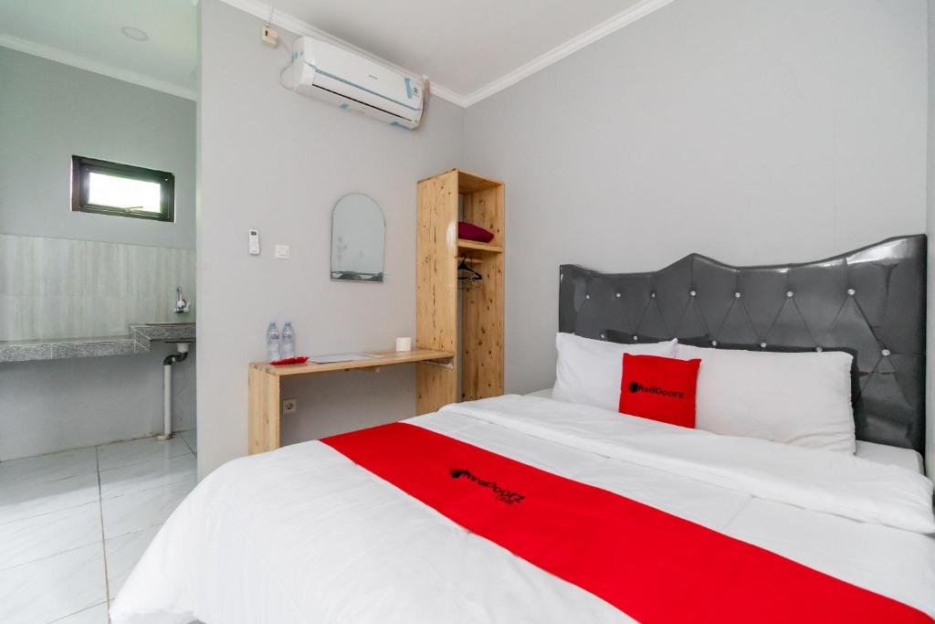 a bedroom with a large white bed with a red blanket at RedDoorz Plus near Jungeland Sentul in Bogor