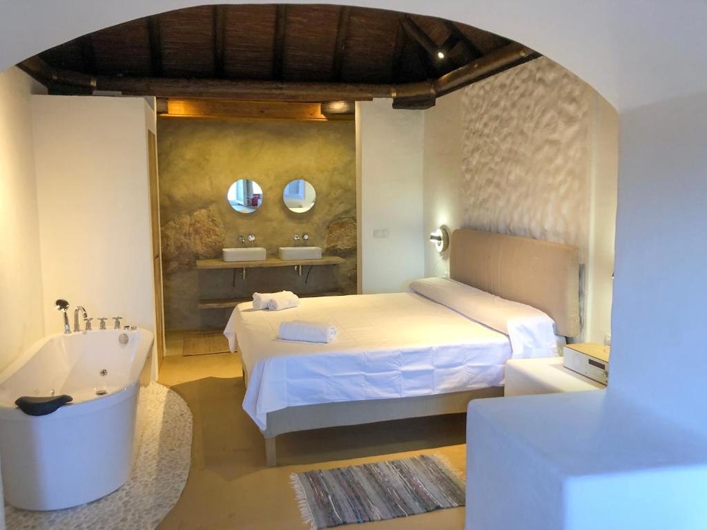 a bedroom with a bed and a tub and mirrors at Casa Cueva El Naranjo Rocabella in El Chorro