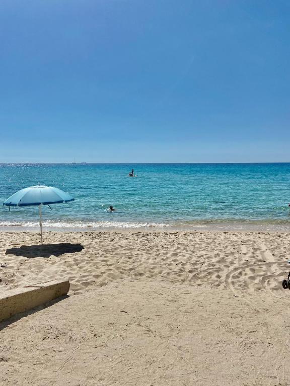 plaża z parasolem i ludzie pływający w oceanie w obiekcie Villa Giancarla Santa Margherita di Pula w mieście Santa Margherita di Pula