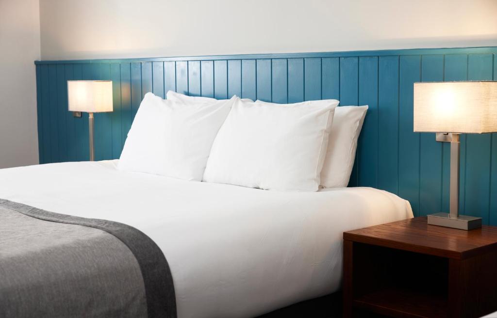 a bedroom with a bed with white pillows and two lamps at Highfield Hotel in Middlesbrough
