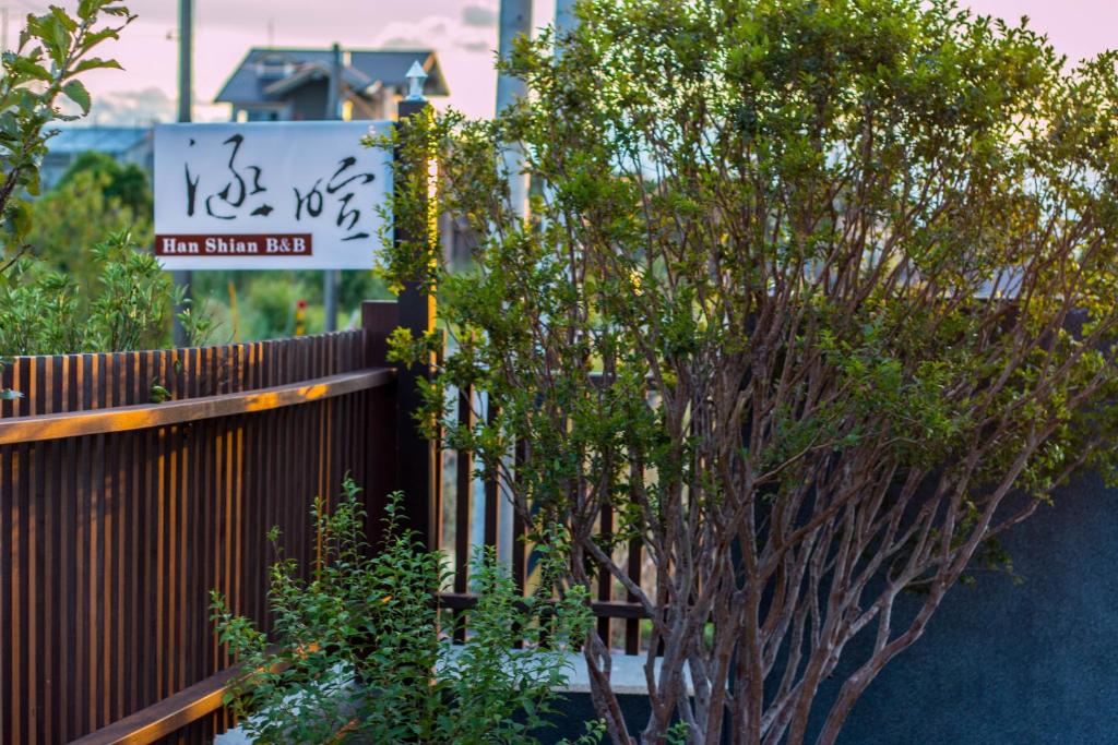a fence with a tree in front of a sign at Han-Shian Boutique B&amp;B in Dongshan