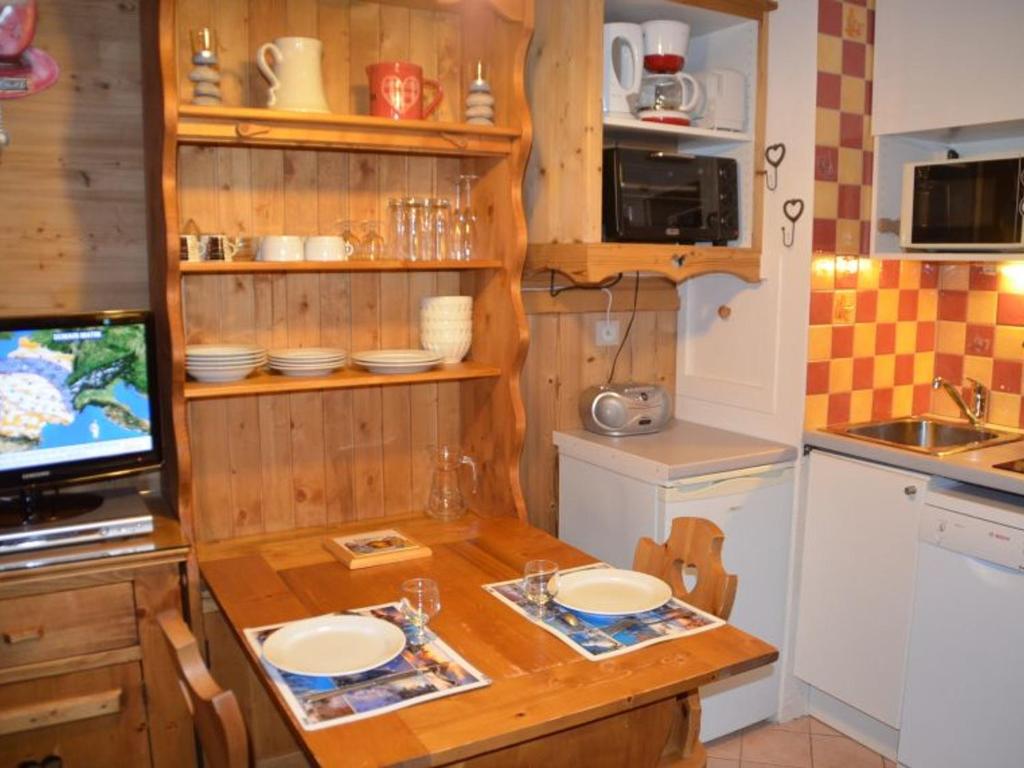een keuken met een houten tafel met borden erop bij Studio Les Menuires, 1 pièce, 2 personnes - FR-1-452-12 in Les Menuires