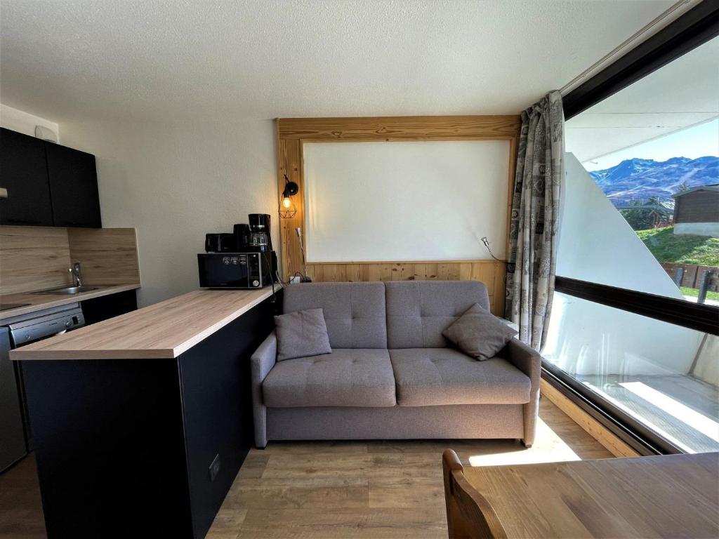 ein Wohnzimmer mit einem Sofa und einem großen Fenster in der Unterkunft Appartement Les Menuires, 2 pièces, 4 personnes - FR-1-452-270 in Les Menuires