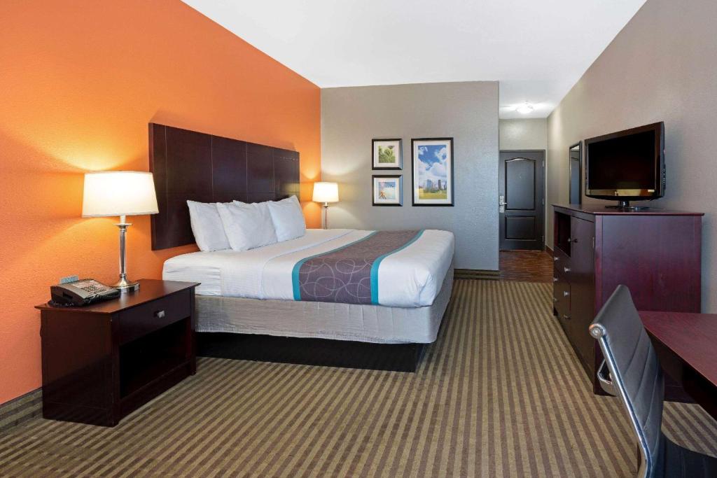 a hotel room with a bed and a flat screen tv at La Quinta by Wyndham Houston IAH Bush Intl Airport E in Humble