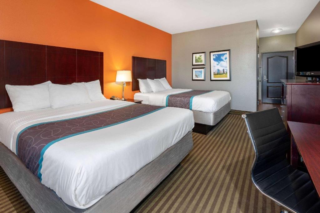 a hotel room with two beds and a flat screen tv at La Quinta by Wyndham Houston IAH Bush Intl Airport E in Humble