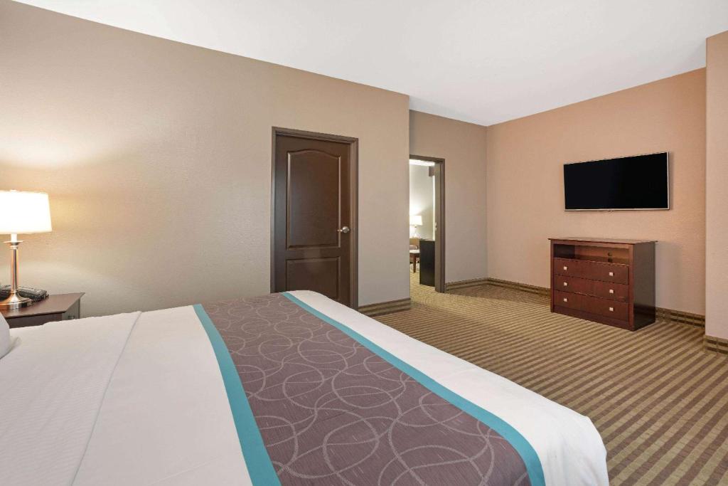 a large hotel room with a bed and a flat screen tv at La Quinta by Wyndham Houston IAH Bush Intl Airport E in Humble