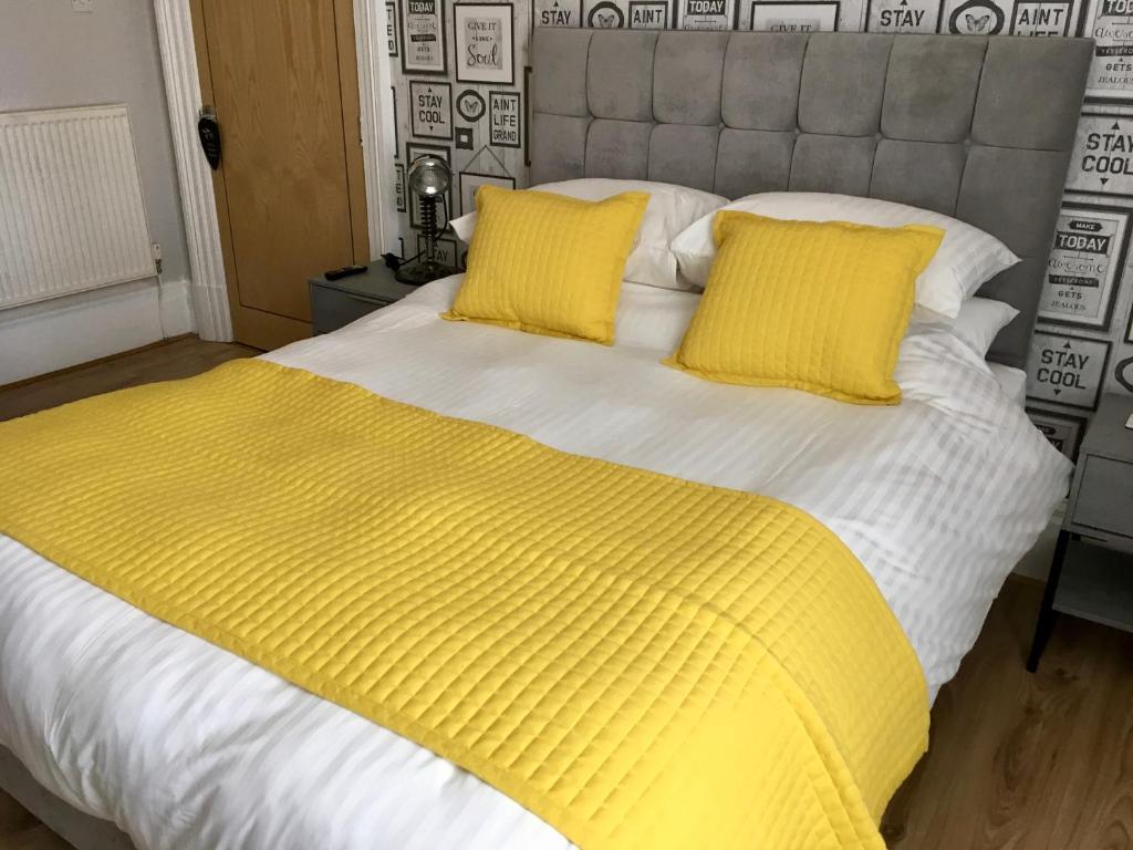 uma cama com duas almofadas amarelas em cima em Cartref Guest House em Carlisle