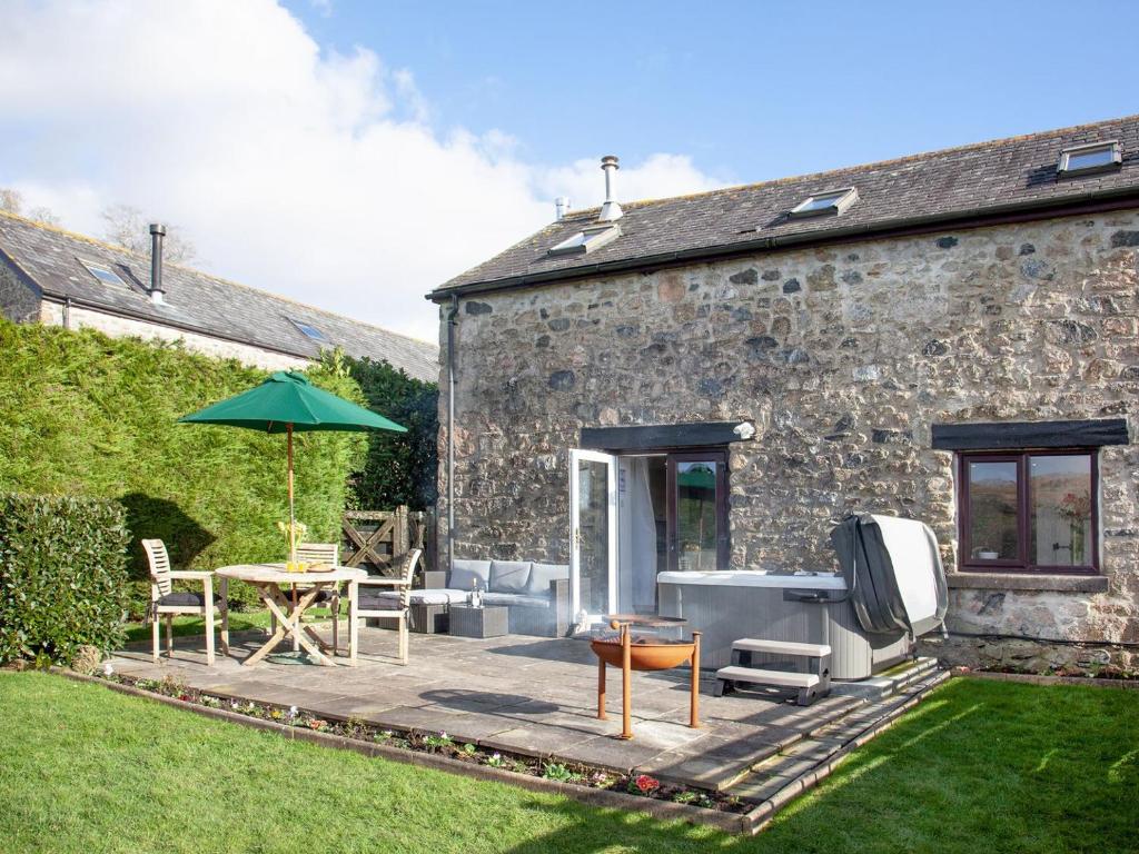 a patio with a table and an umbrella at Dunstone Cottage in Shaugh Prior