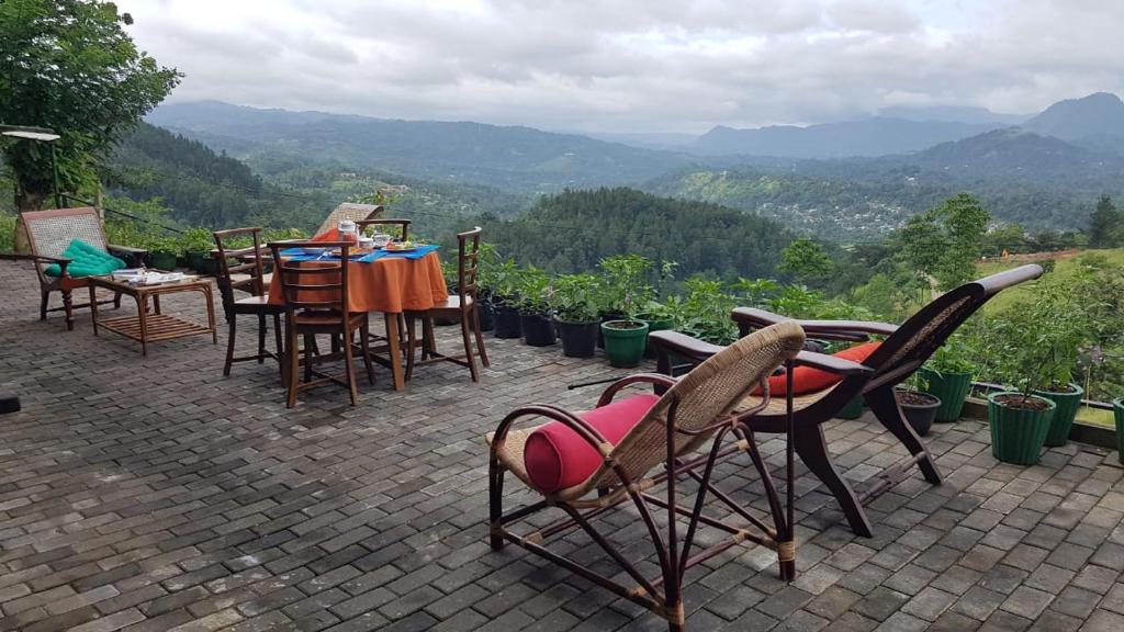 eine Gruppe von Stühlen und Tischen auf einer Terrasse mit Bergen in der Unterkunft Kandy Hindagala Retreat - Boutique Villa in Kandy Hills Sri Lanka in Kamburadeniya