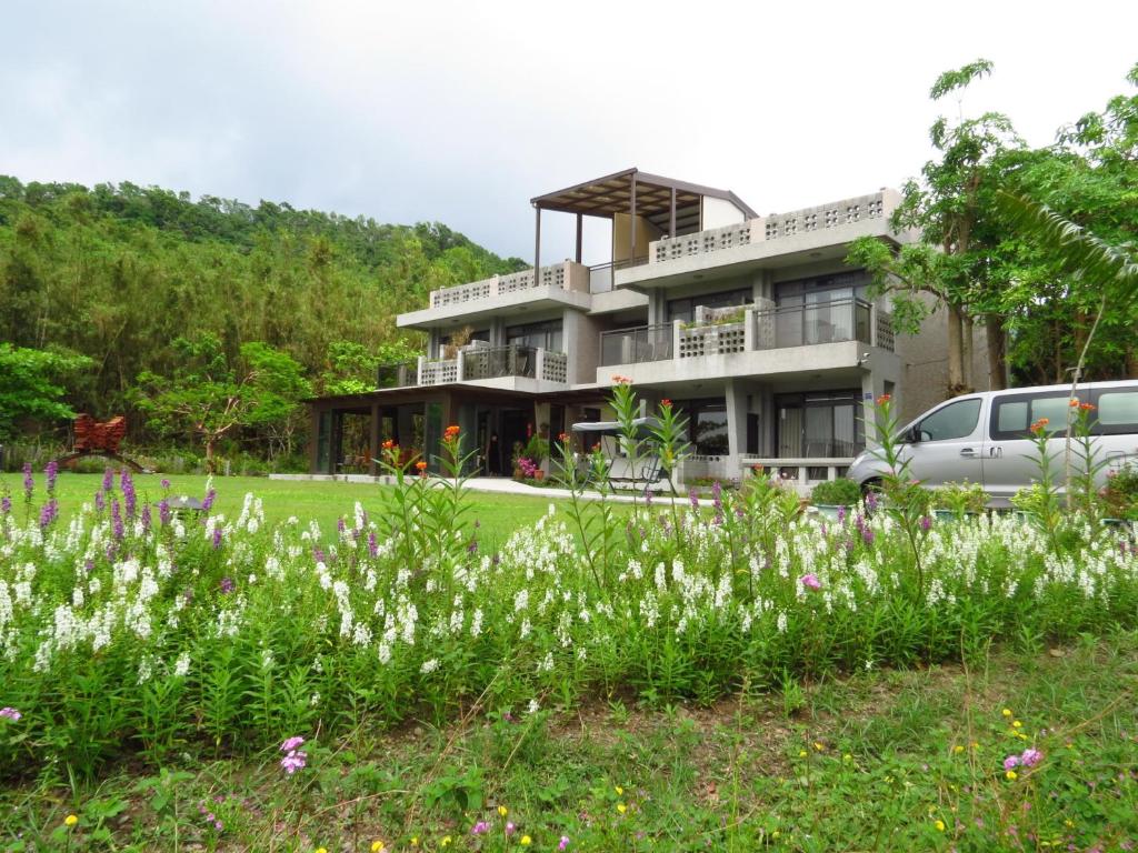 a house with a field of flowers in front of it at Butterfly B&amp;B in Manzhou