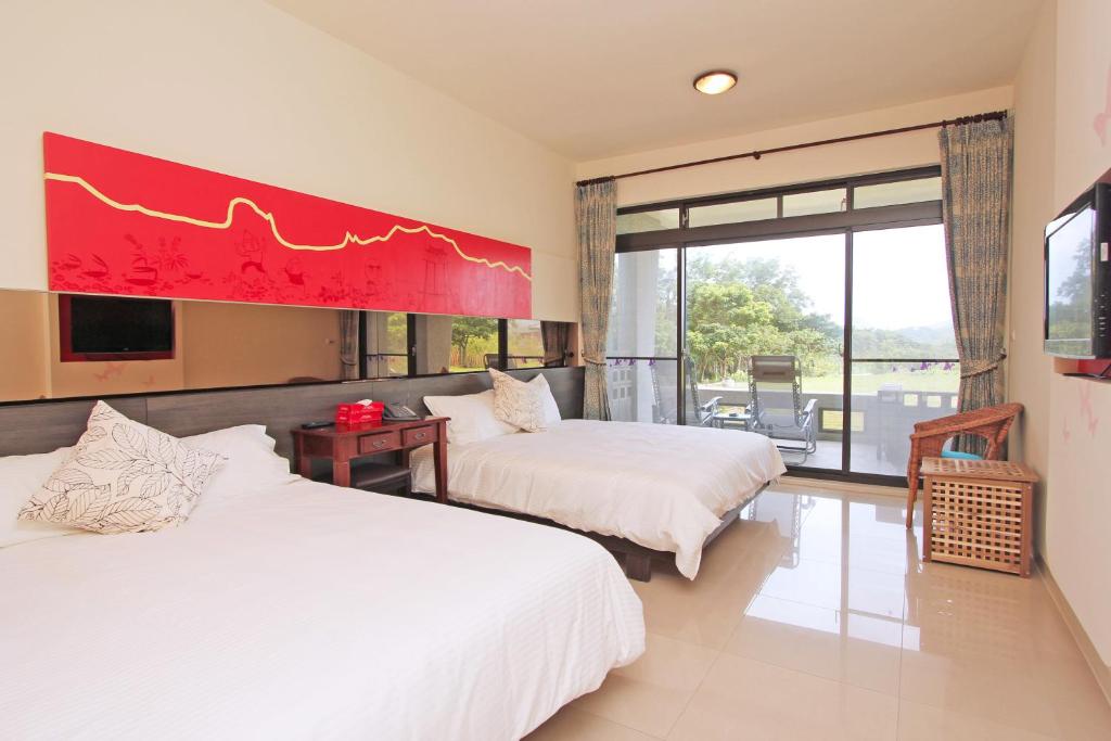 a hotel room with two beds and a large window at Butterfly B&amp;B in Manzhou
