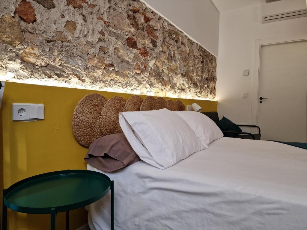 1 dormitorio con cama blanca y pared de piedra en El 32, en Lorca