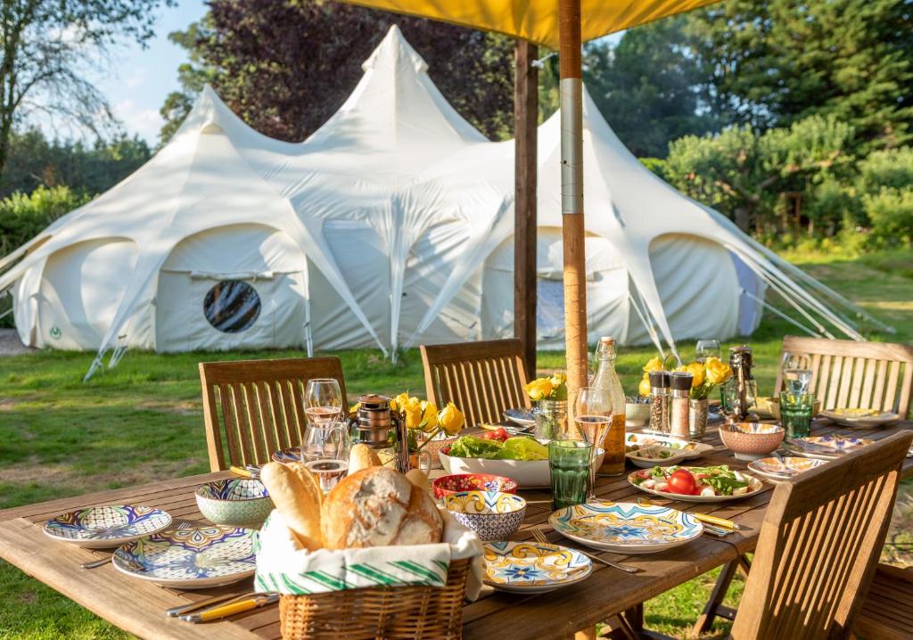 a wooden table with food on it with tents in the background at 8-Bed Lotus Belle Mahal Tent in The Wye Valley in Ross on Wye
