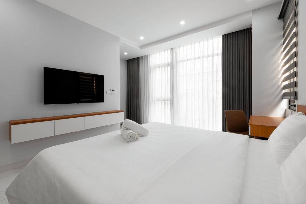a white bedroom with a large bed and a flat screen tv at Lakeside House 3 in Hanoi