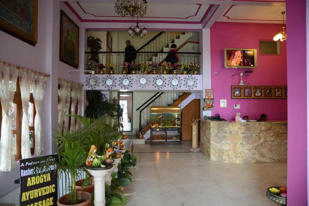un vestíbulo de un edificio con paredes rosas y una escalera en A Palace on River ( Rashmi Guest House ), en Varanasi