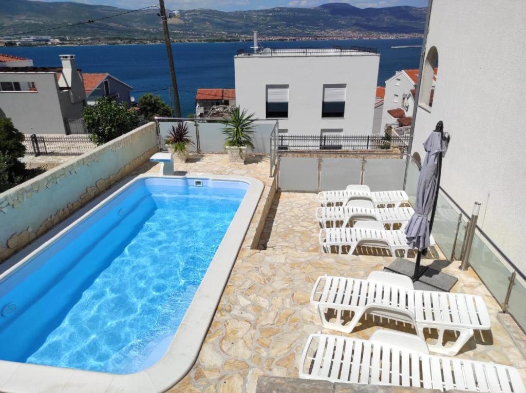 a pool on the roof of a house with chairs at Apartments Sollis in Trogir