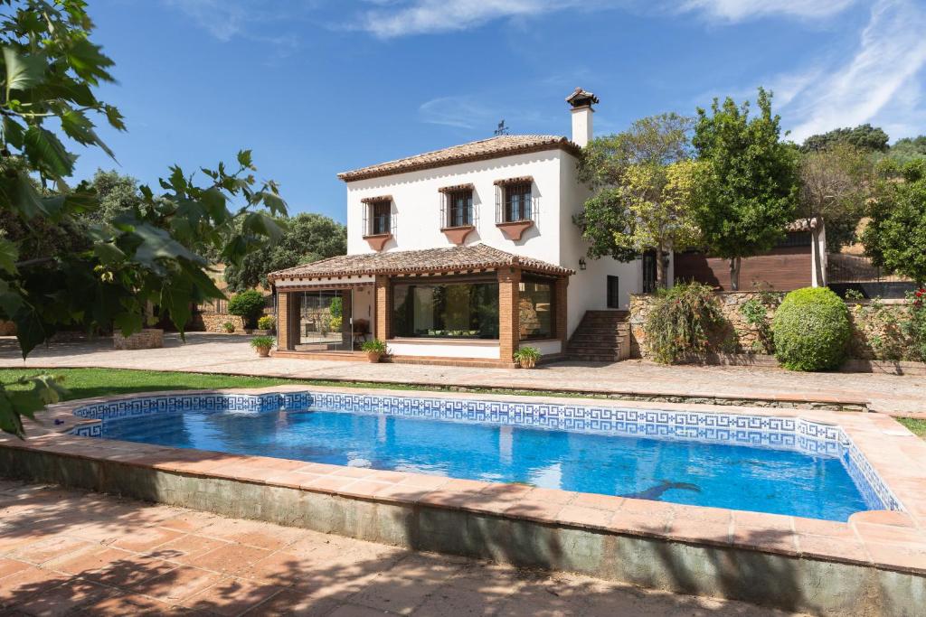 a villa with a swimming pool in front of a house at El recreo de Martalia in Ronda