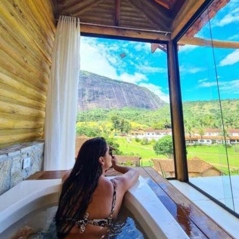 una mujer en una bañera con vistas a la montaña en Hotel Fazenda Santa Helena en Simão Pereira