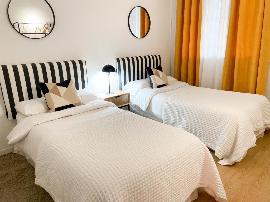 two beds in a room with orange curtains at Apartamento Brisas in Seville