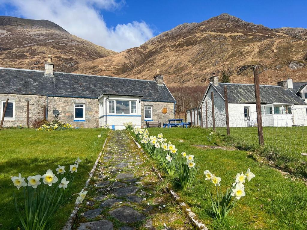 a house with a bunch of flowers in the yard at Cuillin Cottage in Arnisdale