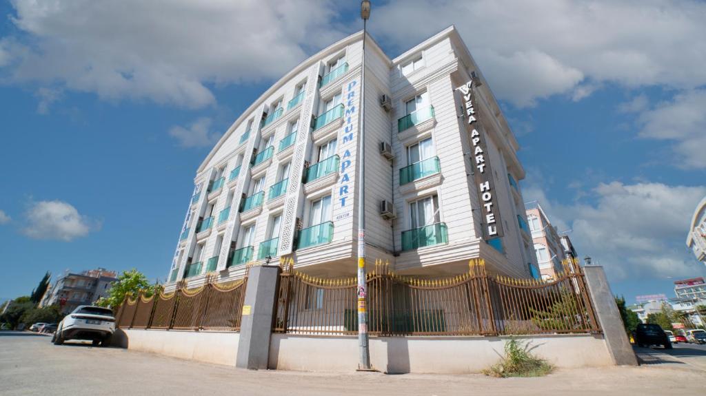 a tall white building with a fence in front of it at Vera Park Premium Apart Hotel in Antalya