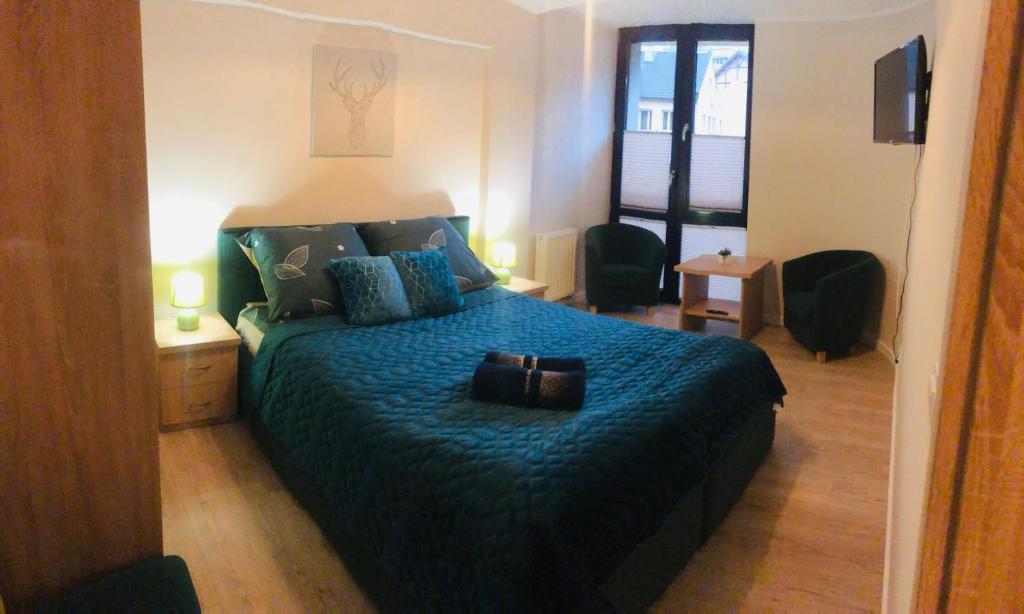 1 dormitorio con 1 cama grande con manta azul en Apartament Bajka, en Krynica-Zdrój