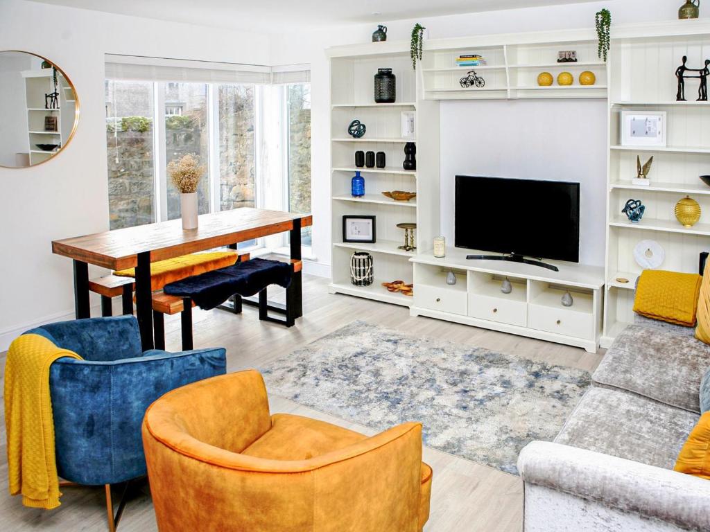 a living room with a table and a tv at Forget Me Not Cottage in Culross