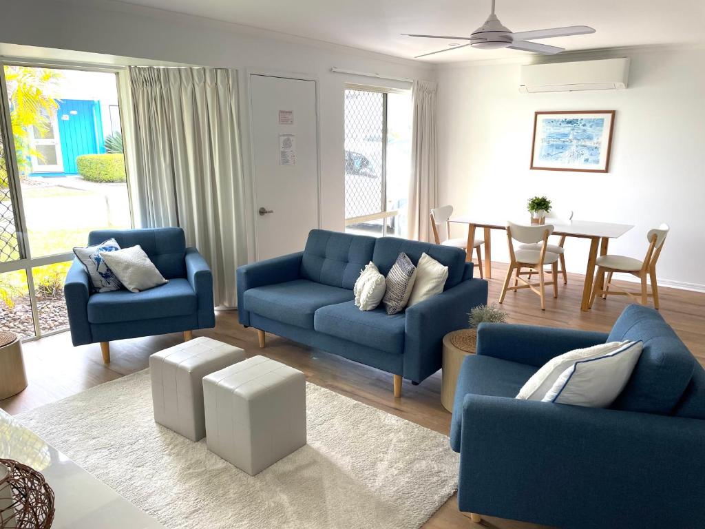 a living room with blue couches and a table at 2 Bedroom Ground Level Villa in Tropical 4* Resort in Noosaville