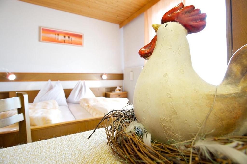 a statue of a chicken sitting on a table in a bedroom at Angerle Alm Apt Rosengarten in Carezza al Lago